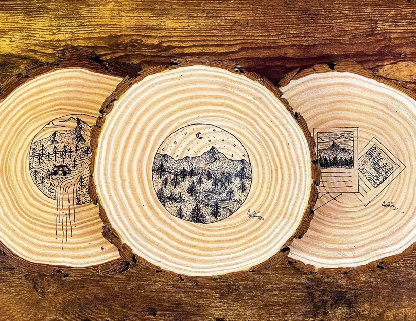 Three wood-slice artworks by Sam Iannone showing mountain and forest scenes