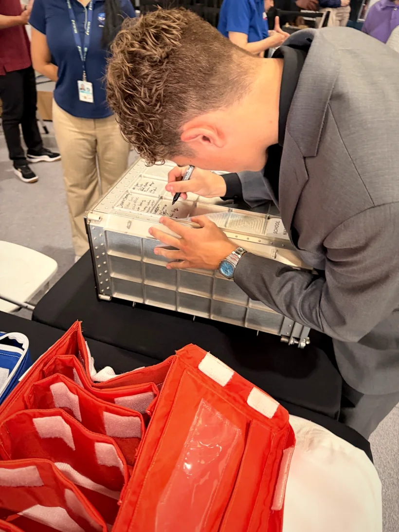 Sam Iannone signing a metal flight locker at the NASA HUNCH event