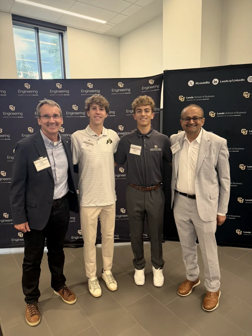 Sam Iannone with a fellow student and two faculty members in front of CU Engineering and Leeds School of Business backdrops
