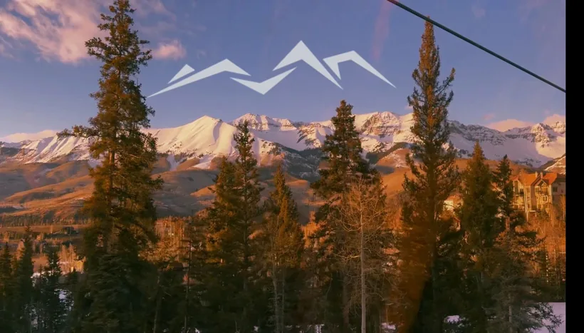 Sam Iannone Ski Company, Sleeper: alpenglow on snowy peaks behind pine trees with the Sleeper mountain logo